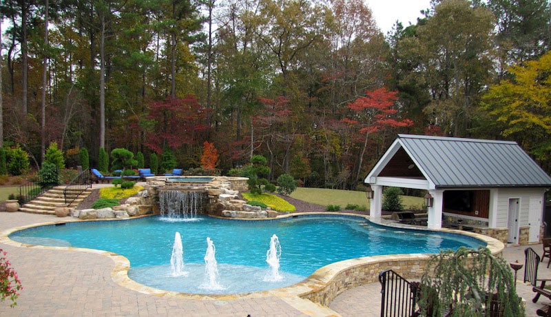 inground pool in a backyard surrounded by trees